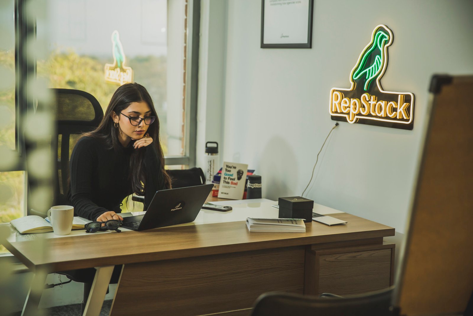 Associate working at desk with RepStack neon sign.